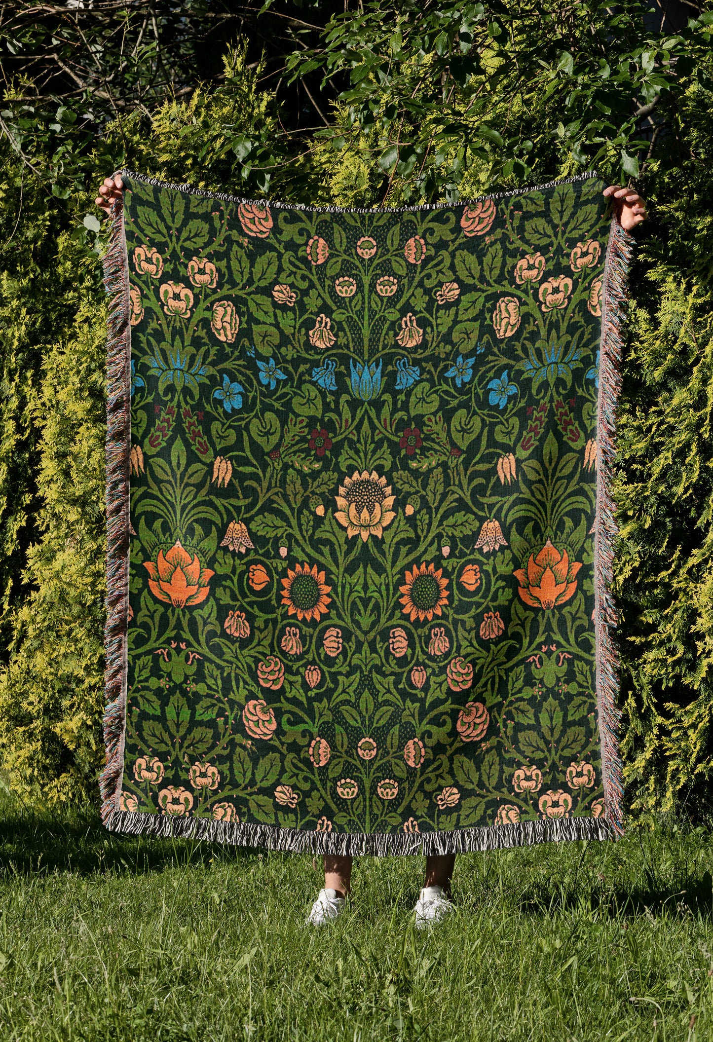 a woman holding up a green and orange quilt