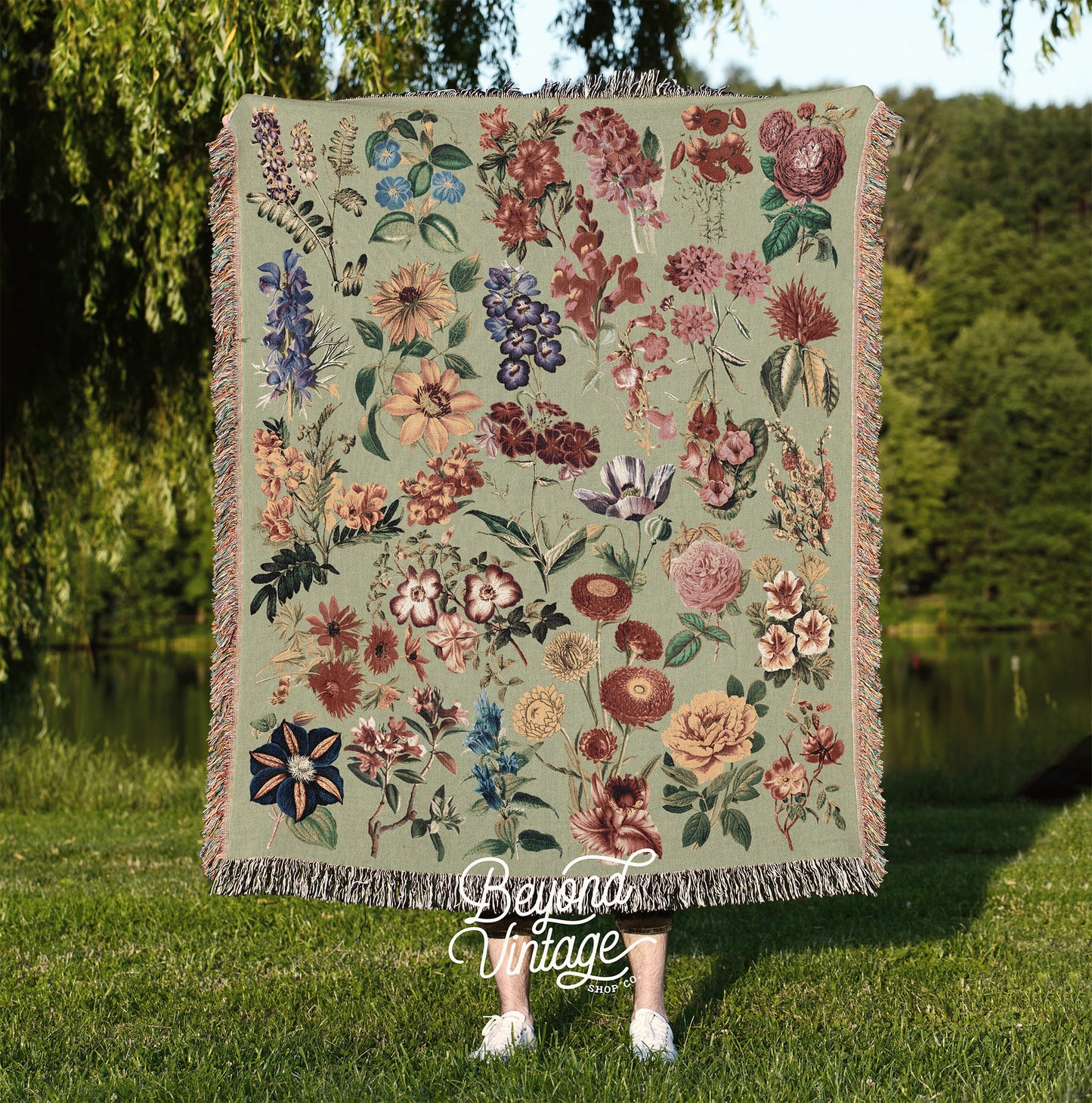 a woman standing in the grass holding a blanket with flowers on it