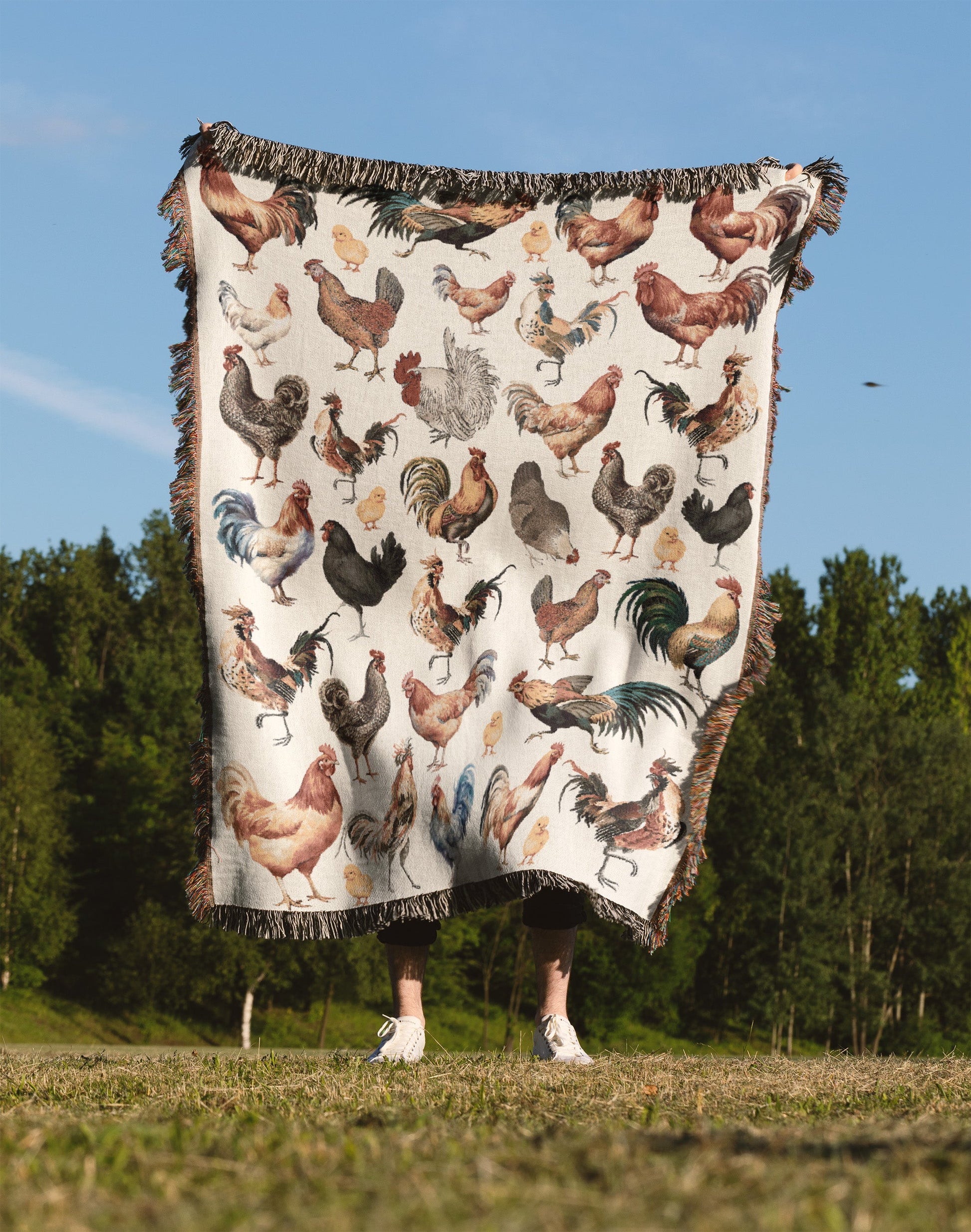 a person standing in a field holding a blanket with chickens on it