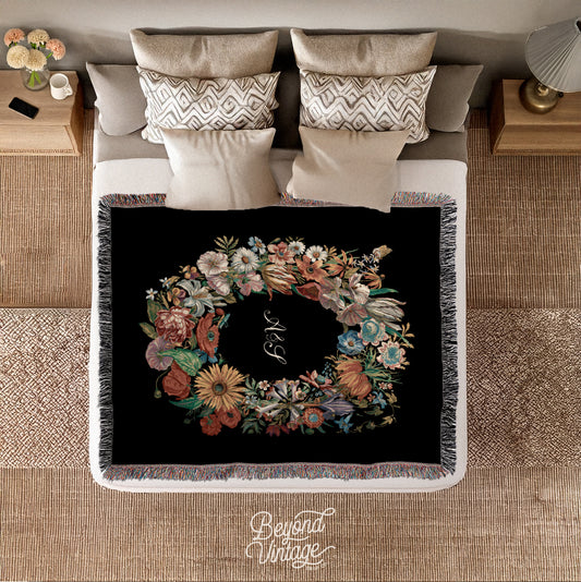 a bed with a black blanket with a floral wreath on it