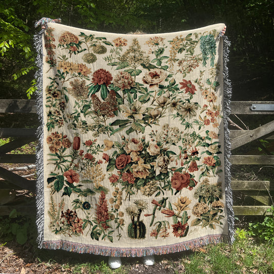 a quilt hanging on a wooden fence in a field