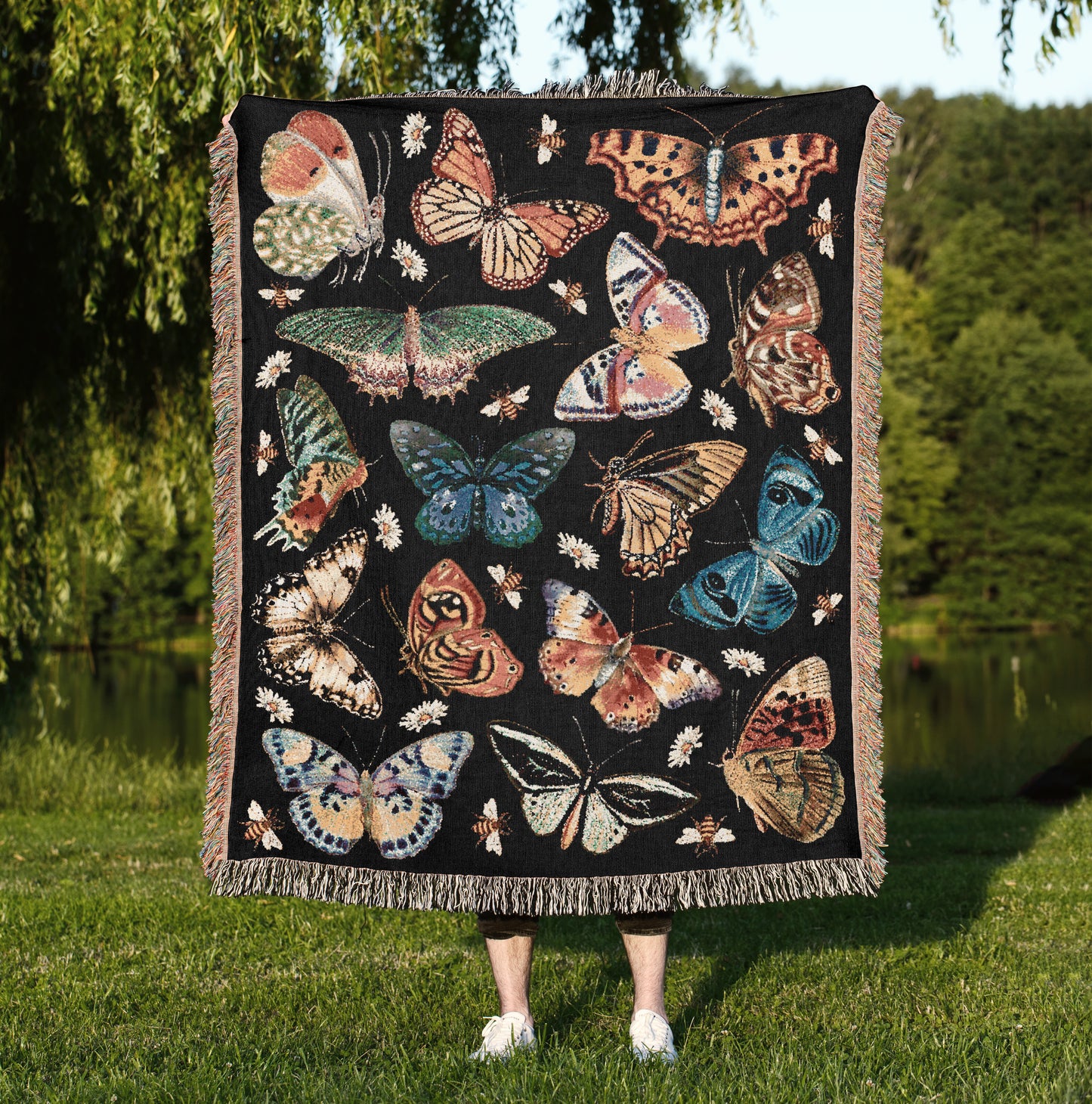 a woman standing in a field holding a blanket with butterflies on it