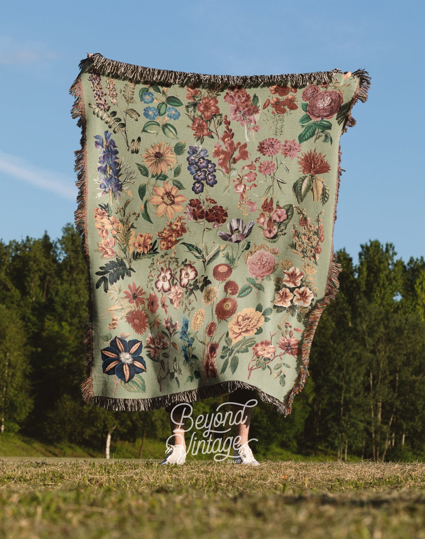 a blanket is hanging in a field with trees in the background