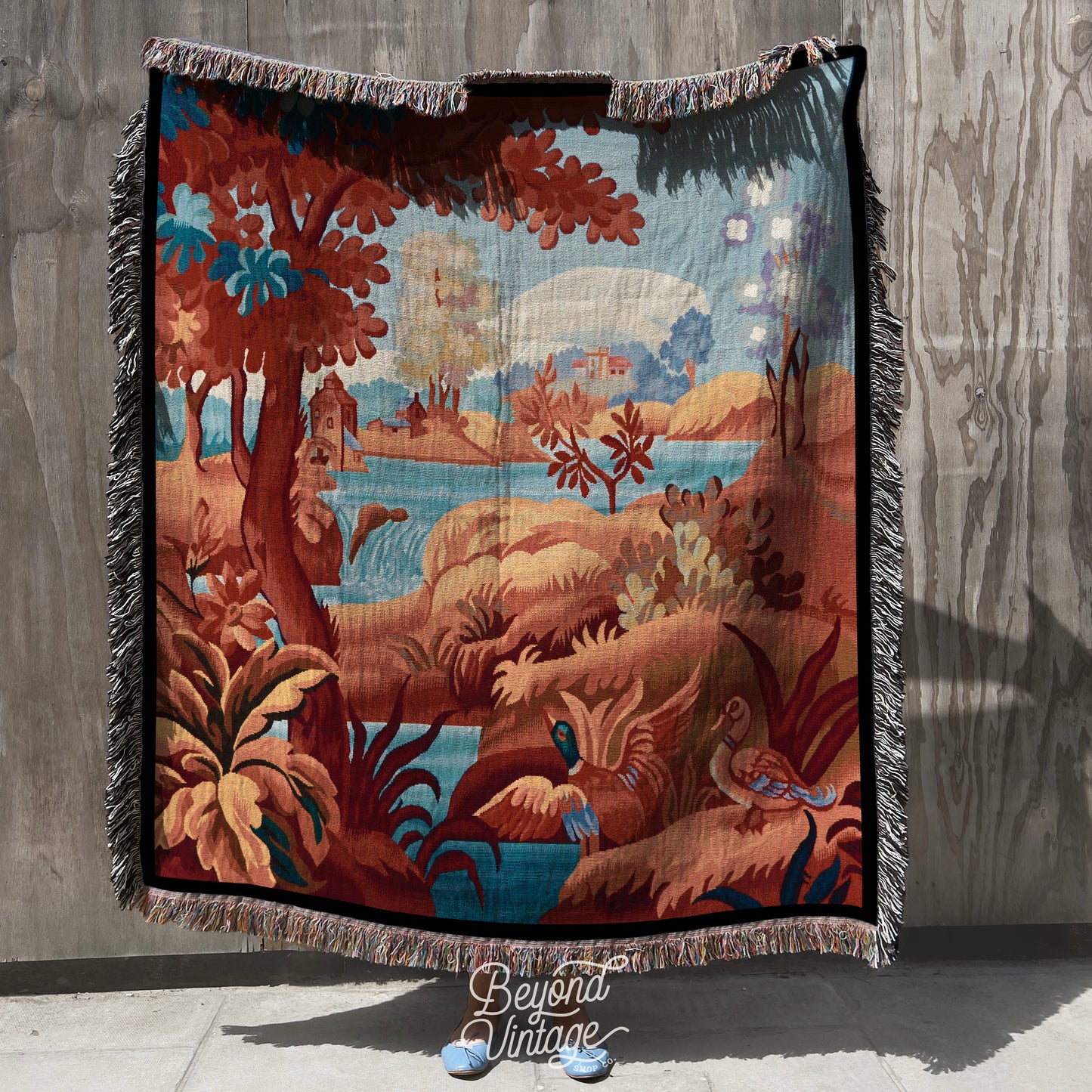 a blanket hanging on a wall with a painting on it