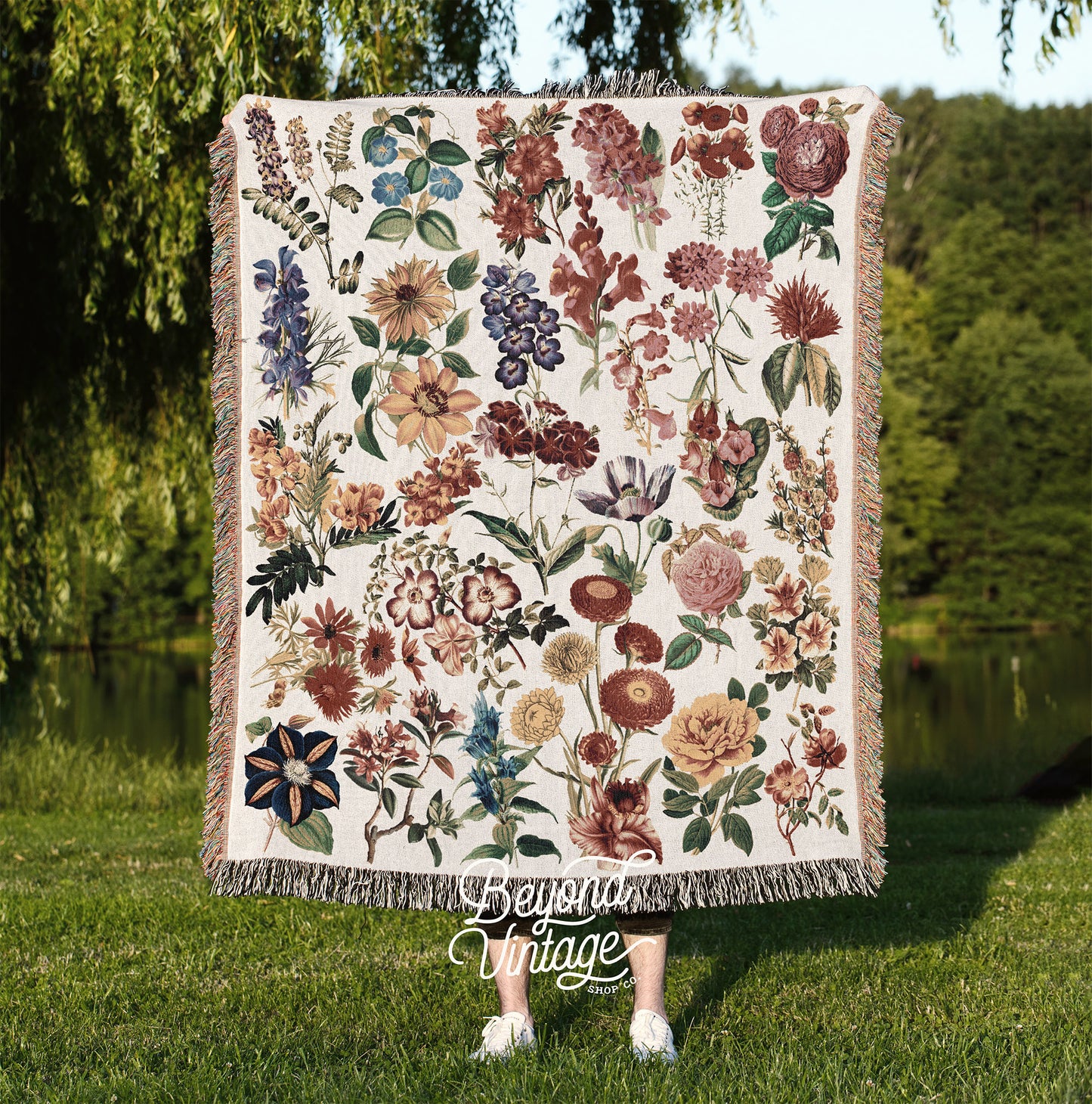 a woman standing in the grass holding a quilt