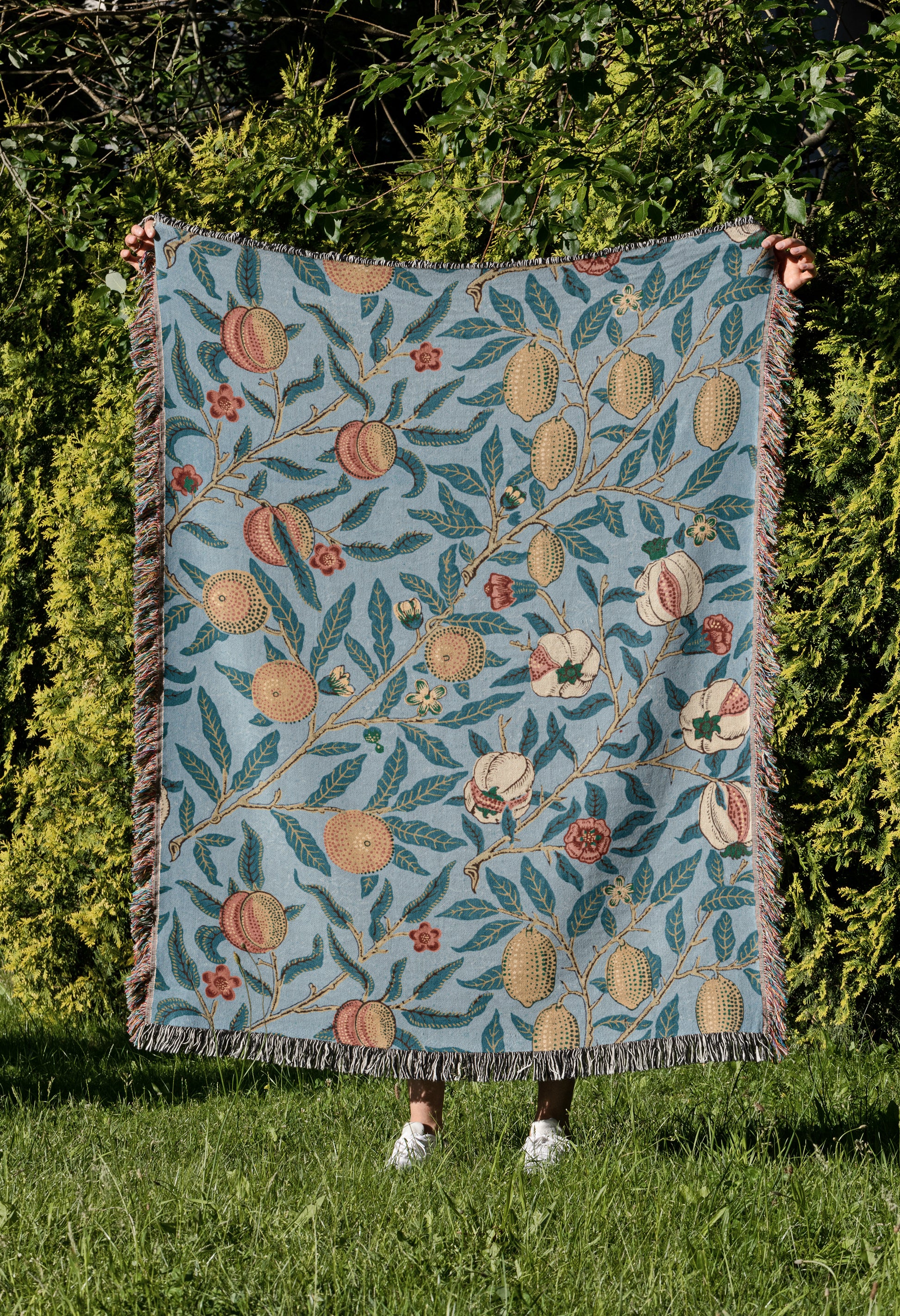 a woman standing in the grass holding a quilt