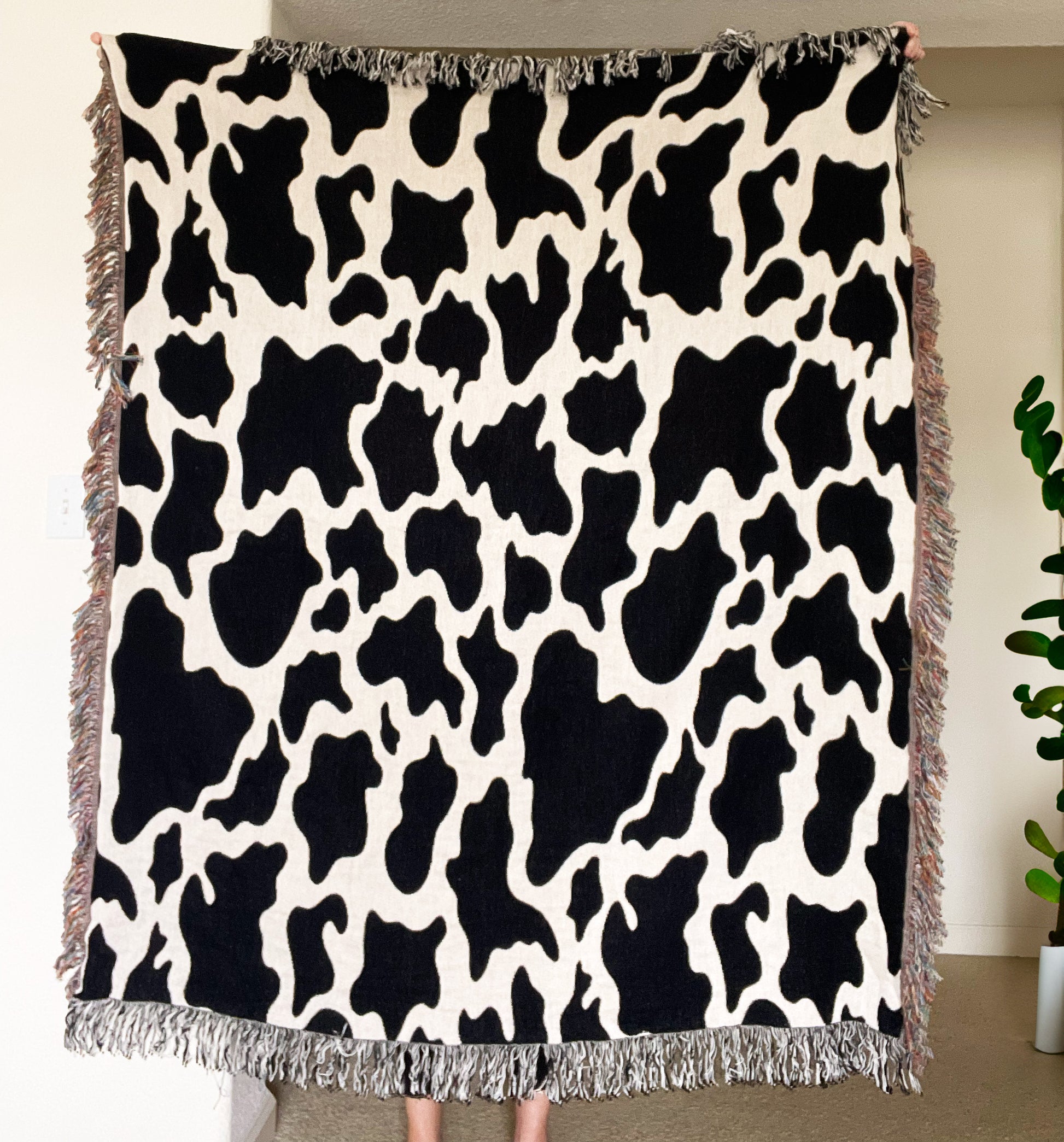 a black and white cow print blanket hanging on a wall