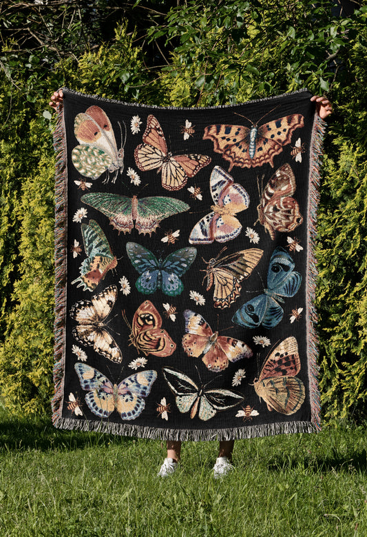 a woman holding up a quilt with butterflies on it