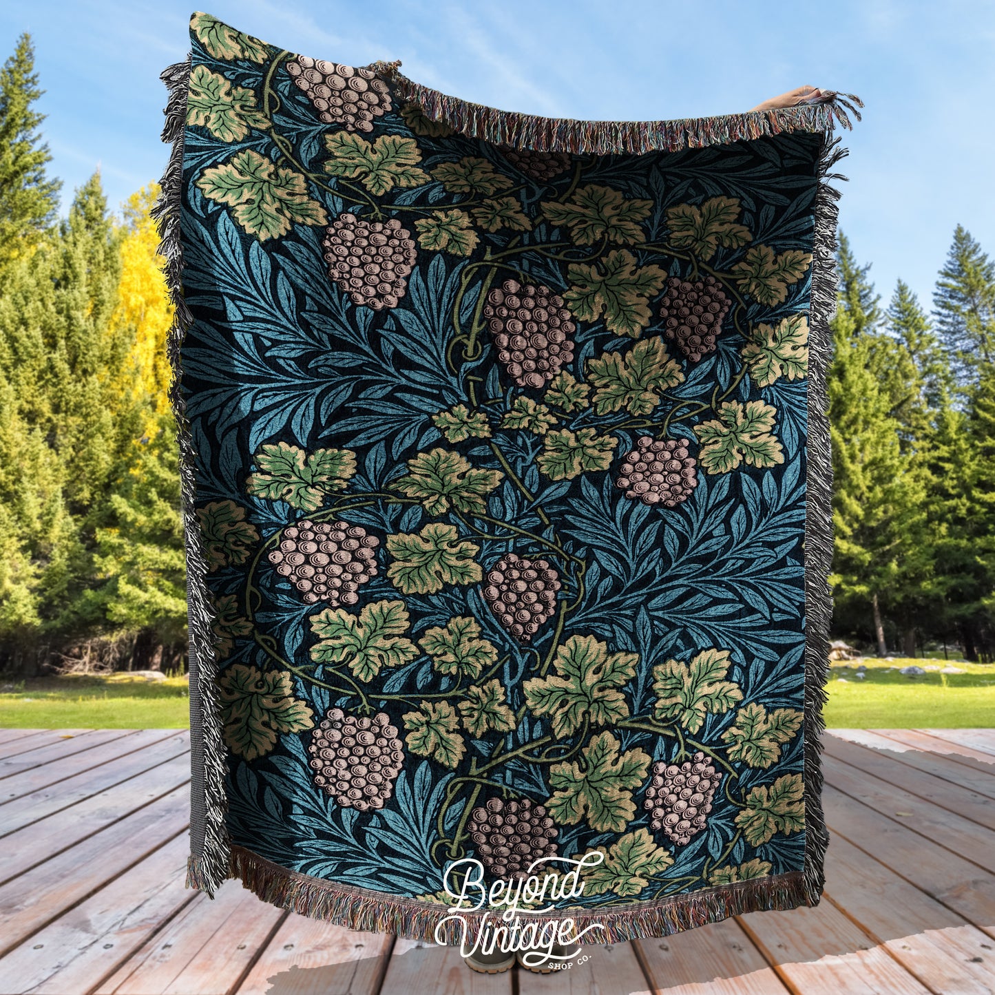 a blanket with pine cones and leaves on a wooden deck