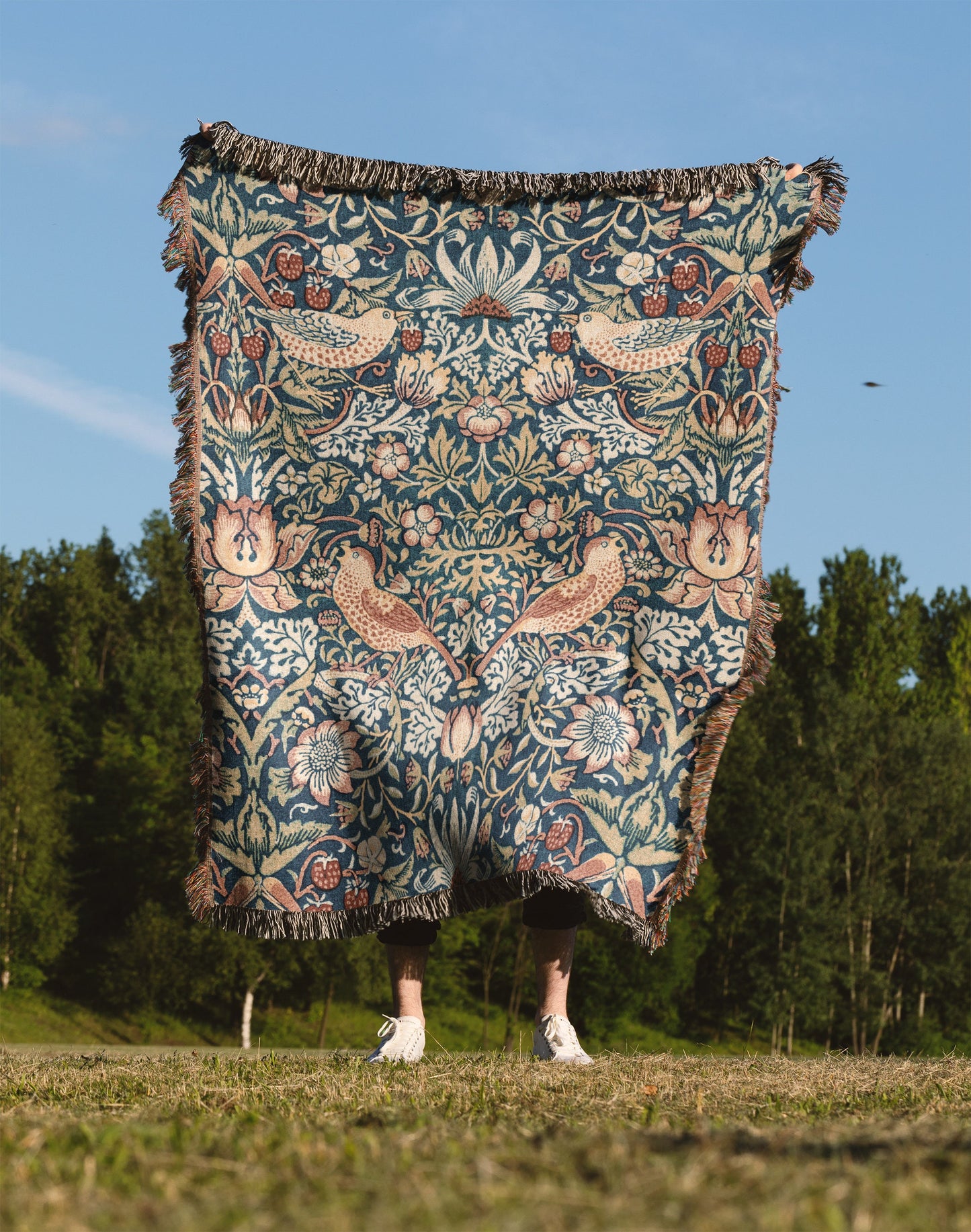 a person standing in a field holding a blanket