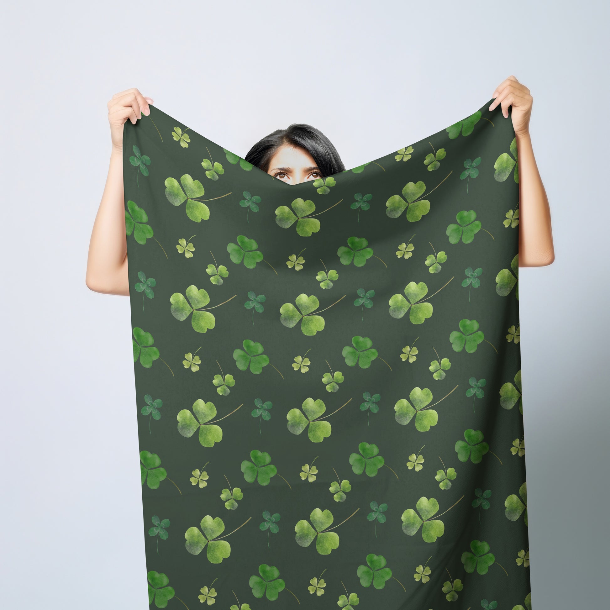 a woman holding up a green scarf with shamrocks on it
