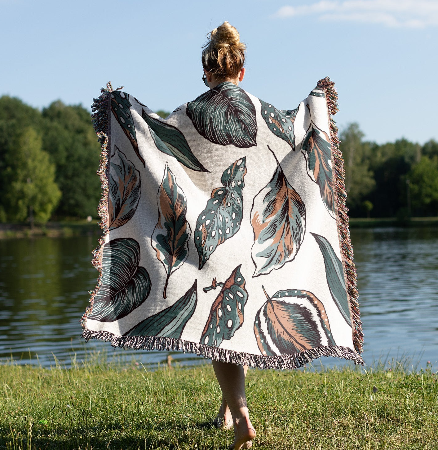 a woman holding a blanket in front of a body of water