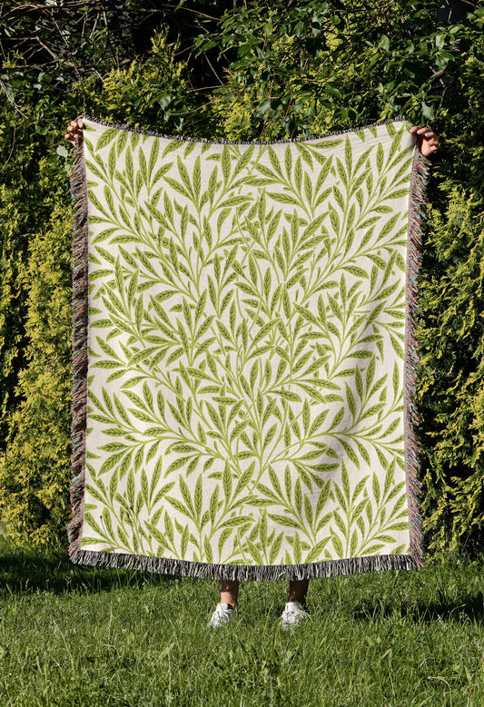 a woman holding up a green and white quilt